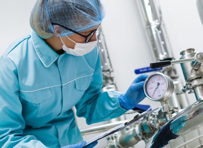 Woman checking gauge on stainless steel tank